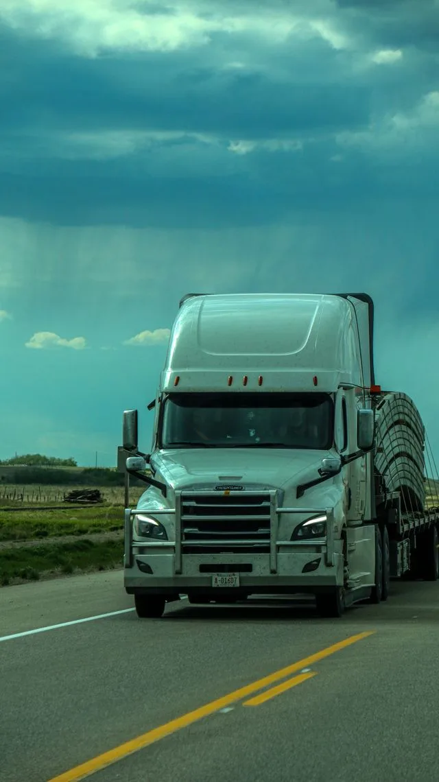 A loaded freight truck on the highway under a stormy sky